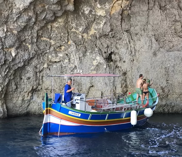 romantic couple on traditional maltese boat in cave in Crystal lagoon , Comino, Malta