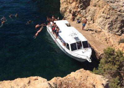 people jumping off boat at comino and having fun